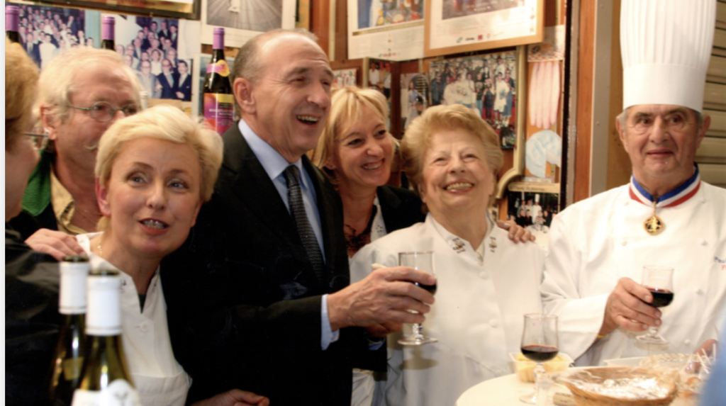 Paul Bocuse et des invités souriants levant leur verre.